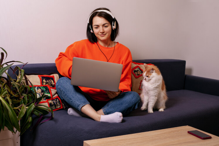 mulher sentada usando um notebook ao lado de um gato